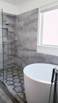 a bath tub sitting next to a window in a bathroom on top of a wooden floor