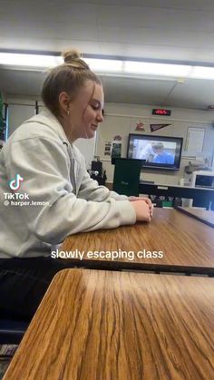 a woman sitting at a table in front of a computer monitor with the caption slowly escaping class