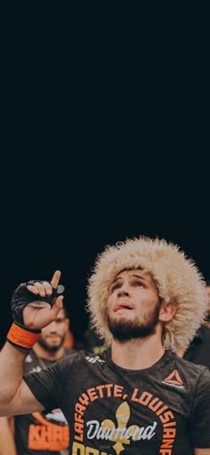 a man with an afro on his head is standing in front of a crowd and pointing to the sky