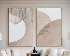 two paintings are hanging on the wall above a white couch and coffee table in a living room