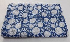 a blue and white cloth with floral designs on the front, sitting on a white surface