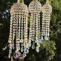 three chandeliers hanging from the ceiling in front of some trees and buildings with lots of crystals on them