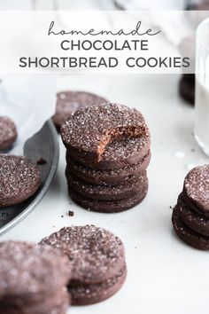 chocolate shortbread cookies are stacked on top of each other with a glass of milk in the background