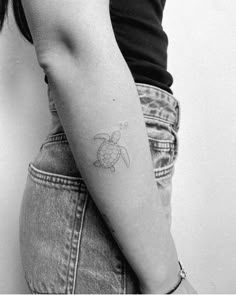 a woman's arm with a small turtle tattoo on the left side of her right arm