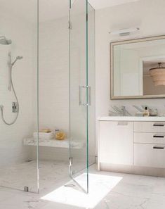 a bathroom with a walk in shower next to a white sink and counter top under a mirror