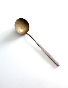 an old spoon is sitting on a white surface with no one around it or the spoon has been used for cooking