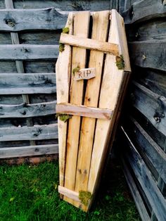 a wooden box with moss growing on it sitting in the grass next to a fence