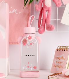 a pink teddy bear sitting on top of a desk next to a bottle with the word safara