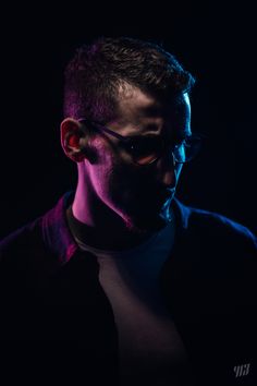 a man with dark glasses and a black shirt in the dark is staring at something