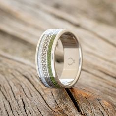 a wedding ring with an intricate design on it sitting on a wooden surface in front of a piece of wood