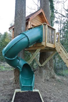 a green slide next to a tree in the woods