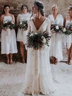 a group of women standing next to each other in front of a brick wall holding bouquets