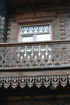 an ornate wooden balcony with decorative iron work on the balconies and above it is a window