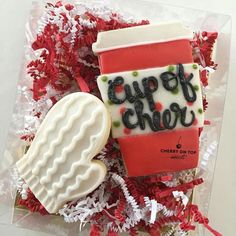 a cup of coffee next to a cookie on top of red and white confetti