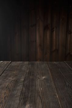 an empty wooden table in front of a wood paneled wall with lights on it