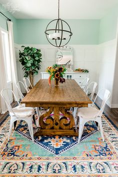 a dining room table with chairs and a rug on the floor in front of it