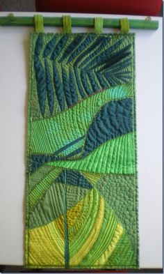 a green and yellow quilt hanging on a wall