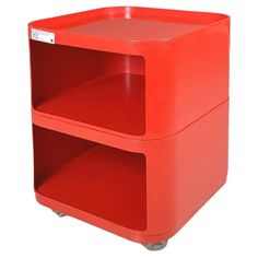 a red plastic storage box with wheels on the bottom and one section open to show shelves