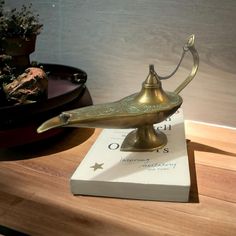 a brass lamp sitting on top of a wooden table next to a potted plant