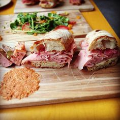 a sandwich cut in half sitting on top of a cutting board next to other food