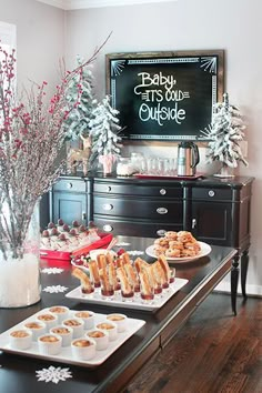 a baby its cold outside party with snacks and desserts on the buffet table in front of a chalkboard