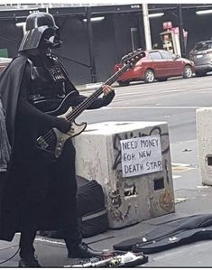 a man dressed as darth vader playing guitar on the street