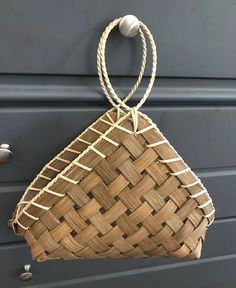 a woven basket hanging on the side of a door handle, with rope attached to it