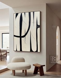 an abstract painting hangs on the wall next to a white chair and footstool