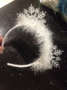 someone is making a snowflake headband out of white feathers on a table