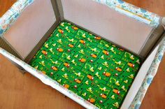 a baby crib that has a green and yellow pattern on the bottom with animals in it