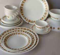 an assortment of white and gold dinnerware with golden designs on the rims,