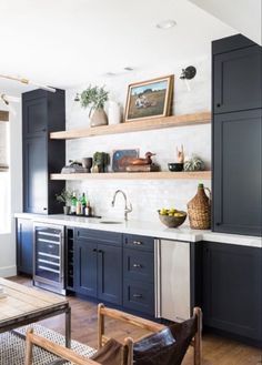 a kitchen with dark blue cabinets and white counter tops, wooden flooring and open shelving