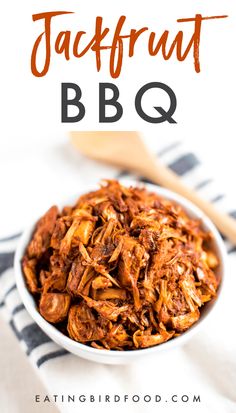 a white bowl filled with bbq next to a wooden spoon on top of a striped towel