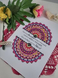 a card with an intricate design on it next to some flowers and crochet doily