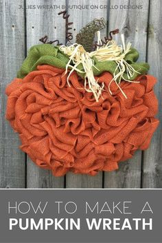 an orange and green pumpkin hanging on the side of a wooden fence next to grass