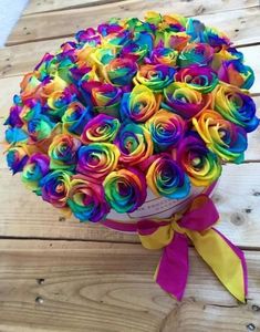 a bouquet of multicolored roses sitting on top of a wooden table