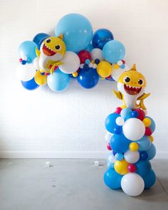 balloons are floating in the air next to a balloon arch that is shaped like a shark