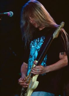 a man with long hair playing a guitar