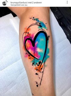 a colorful heart tattoo on the right thigh with watercolor splatters and ink