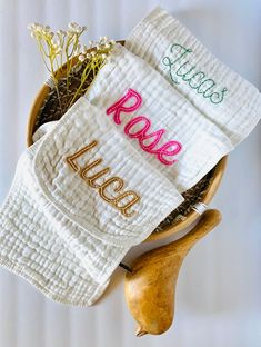 two personalized towels are placed in a bowl with some wood utensils next to it