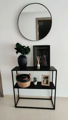 a black shelf with a mirror, plant and pictures on it next to a potted plant