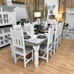 a white table and chairs in a room with wood flooring, cabinets and pictures on the wall