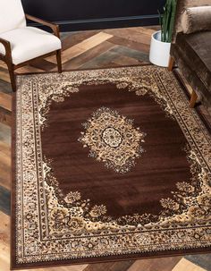 a brown area rug with an ornate design on the center and bottom, in front of a white chair