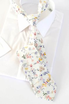 a white shirt with a flowered tie on top of it and a white dress shirt