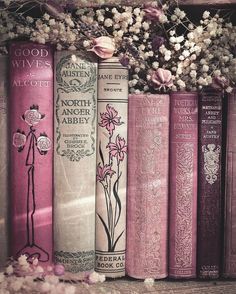 some books are lined up next to each other on a shelf with flowers in them