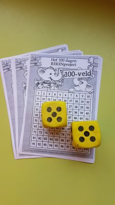 two yellow dices sitting on top of each other next to some sheets of paper