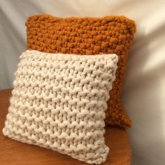 two crocheted pillows sitting on top of a wooden table