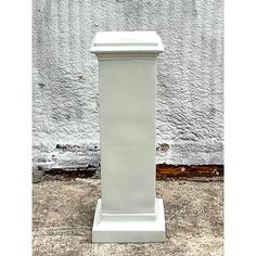 a white pedestal stands in front of a wall