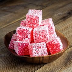 a wooden bowl filled with sugar cubes on top of a table