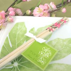 a pair of chopsticks sitting on top of a notepad next to pink flowers